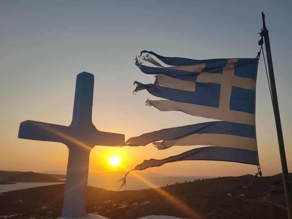 Bandiera greca al tramonto su una chiesetta delle isole